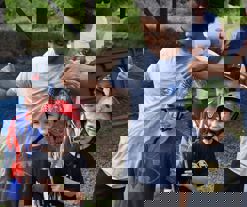 A group of skateboarders smiling in front of a skate park.